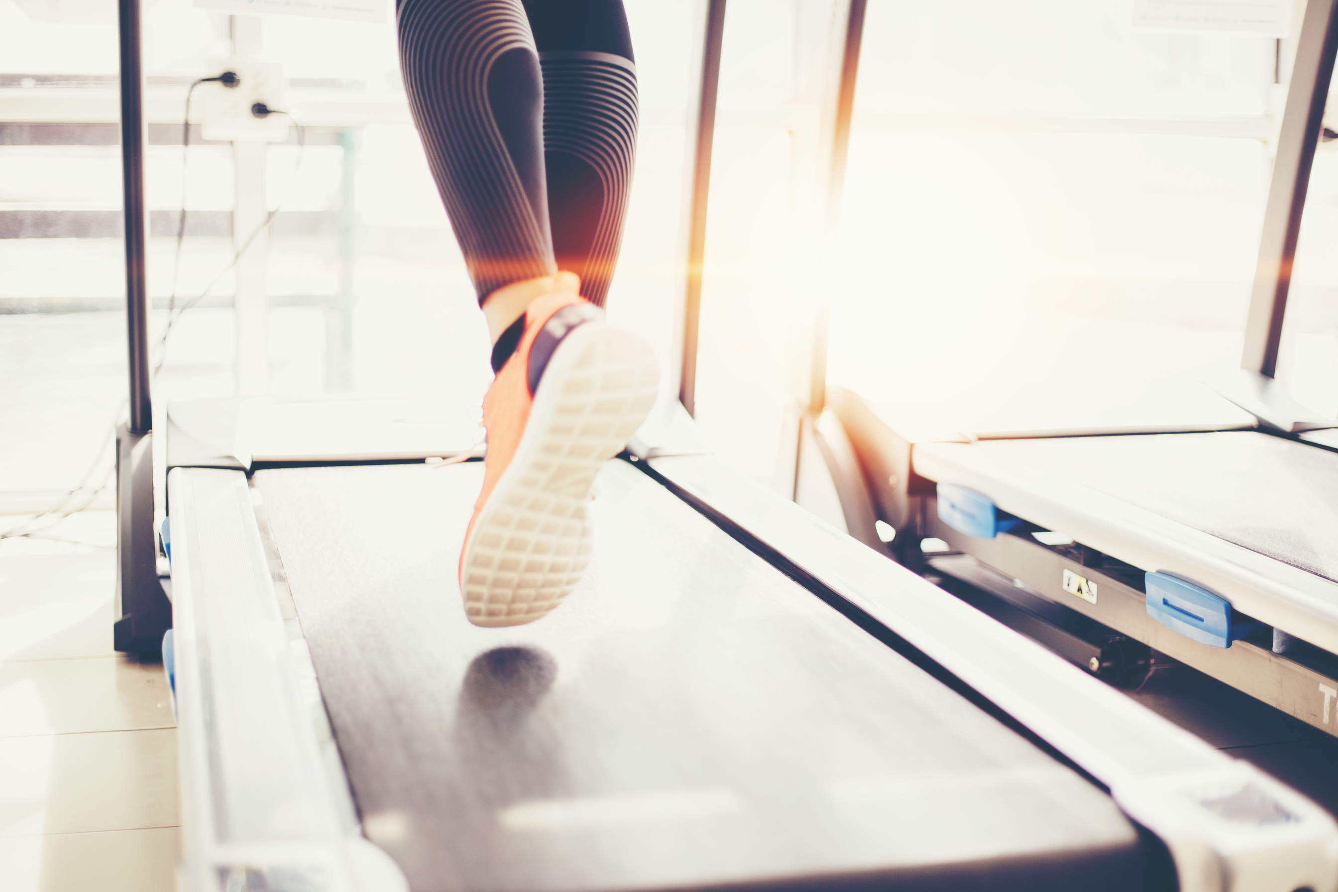 Low Section Of Woman Running On Treadmill At Gym