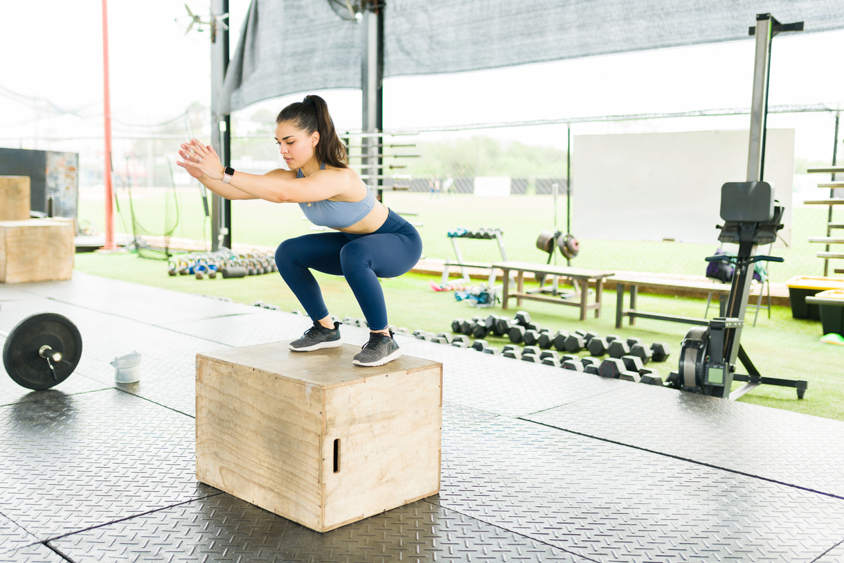 Active woman exercising with squat exercises on a plyo box