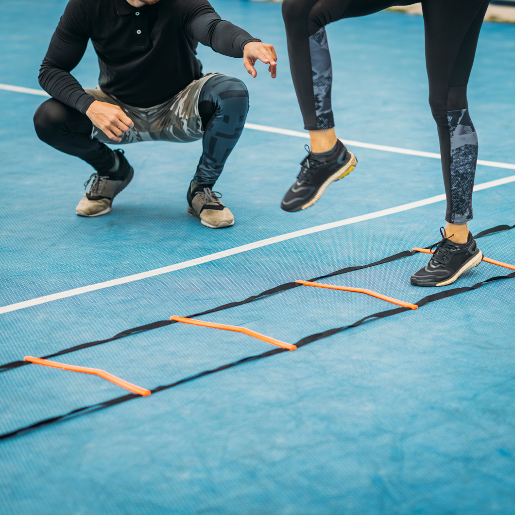 Young Woman Exercise using Agility Ladder, working with Fitness Coach